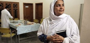 Maryam Bibi, a Pakistani woman, wearing a white shawl and holding a book.