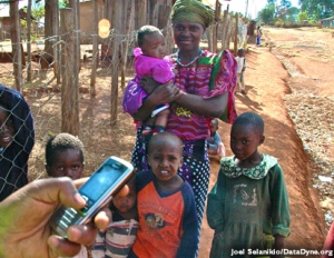 A man holds a cell phone in front of a woman with four children.